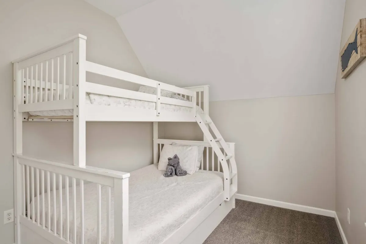 A playful bunk room with a sturdy bunk bed, plush soft toys, and a textured carpet. The scene is warm and inviting, making it perfect for children or families. The environment is designed for both sleep and play, inviting late-night giggles and bedtime stories.